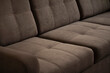 © Anton - A soft sofa made of brown velour with quilted stitched pillows with a comfortable back and seat. Upholstered furniture close-up with copy space.
