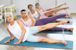 © JackF - Elderly woman lies on mat and performs stretching exercises with resistance bands in a group pilates class