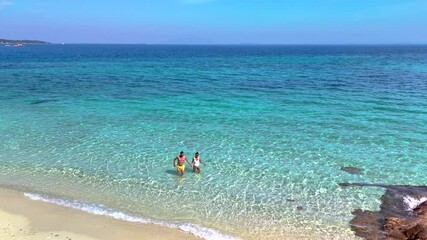 Wall Mural - Explore the tranquil shores of Koh Munnork Island where turquoise waves gently lap against soft sands. A divers couple of man and woman walks in the ocean