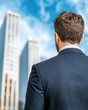© CHONCHANOK PHOTO - A businessman in a suit standing in front of modern skyscrapers, contemplating his career and future in an urban environment.