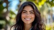 © Wannaeka - Cheerful close-up portrait of young woman with long dark hair smiling in natural park setting.