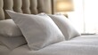 © Atthapon - A bed with white pillows and a lamp on the nightstand