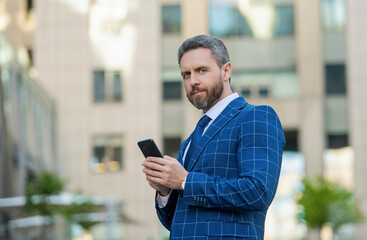 Canvas Print - Successful businessman business man in formal suit standing outdoor at the office using phone