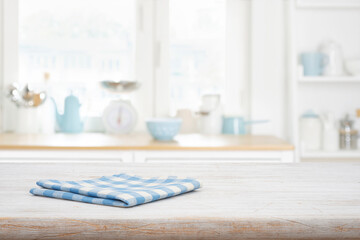 Wall Mural - Blue checkered napkin on bleached wooden table with blur kitchen interior background