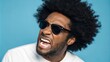 © IbragimovN - Man with afro and sunglasses expressing enthusiasm against blue background