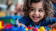 © DKPhoto - A delighted toddler playing with vibrant building blocks, showcasing creativity and joy in a playful environment filled with imagination and excitement.