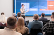 © Anton Gvozdikov - Speaker delivers engaging presentation in front of attentive audience, highlighting key points on large screen.