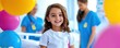 © fair - A cheerful girl in a hospital setting celebrates with colorful balloons, accompanied by caring healthcare professionals in bright uniforms.