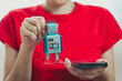 © JK_kyoto - person in red shirt holds vintage toy robot and smartphone, showcasing blend of nostalgia and modern technology. robot features colorful buttons and clock