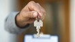 © daniel - Professional hands over a key during a real estate transaction at an office