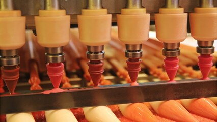 An array of precision coating nozzles positioned above an assembly line each designed for different materials and layers illustrating the versatility of the technology.