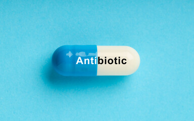 Wall Mural - Capsule with word Antibiotic on light blue background, top view