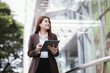 © Witoon - Elegant Asian woman in formal suit talking to someone or using mobile app on smartphone.