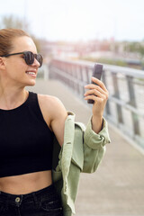 Wall Mural - Urban woman in sunglasses with mobile phone outdoors in urban settings.