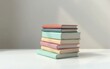 © Inna - Stack of colorful books with pastel covers arranged on a white table against a bright background