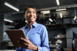 © insta_photos - Happy busy professional African American business woman company manager sales executive wearing blue shirt holding fintech tab using digital tablet computer standing in office working on pad.