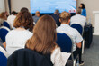 © tsuguliev - Female participants audience at the symposyum meeting, attendees in conference room hall listens to lecturer, group of women on a congress together listen to speaker on a stage at master-class