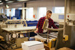 © Geber86 - Focused male worker inspecting large printouts in industrial printing facility