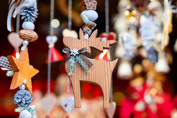 Rustic wooden Christmas decorations featuring reindeer and star, adorned with small pinecones and festive greenery. Ornaments are hanging surrounded by other seasonal holiday decor in festive setting