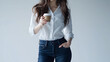 © Tanakrit - A woman in a white shirt and blue jeans holding a coffee cup