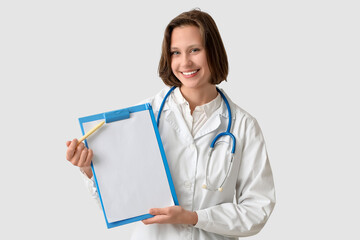 Poster - Beautiful female doctor with clipboard on white background