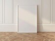© PERFECTisME - A blank white picture frame on a white wall and hardwood floor