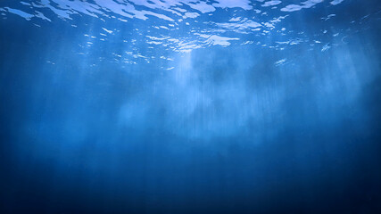 Wall Mural - Underwater photo of rays of sunlight coming through the surface of the blue ocean. From a scuba dive - Unspecified.