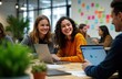 © Viktor - Group of young women, men work together happily on laptops in modern office. Collaborating on project. Casual atmosphere suggests hackathon session. Women smiling, engaged in conversation. Sitting