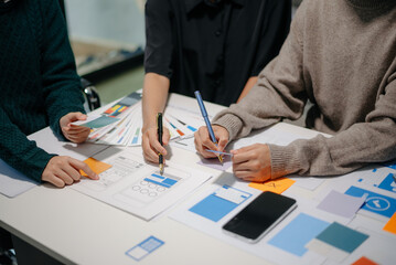 Wall Mural - close up view of ui developer team brainstorming on their project with laptop, smartphone and digita