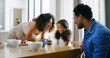 © peopleimages.com - Parents, girl and happy with candle on cupcake for birthday celebration and support at home. People, interracial family and dessert with kid on memories, special occasion in bonding, love and smile