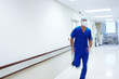 © peopleimages.com - Man, surgeon and running in hospital hallway to emergency room for operation, crisis or duty in scrubs. Person, doctor and motion blur with speed, corridor and healthcare services with mask at clinic