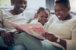 © peopleimages.com - Black family, home and reading story book with kid, fairytale and support toddler in education. Love, parents and listening to fantasy literature in lounge, learning language and bonding together