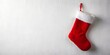 © Anelya - Red Christmas stocking hanging on a white wall in a festive holiday setting during the winter season