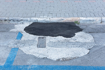 old damaged and worn asphalt road with pothole filled with new bitumen