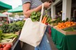 © tatchaihot - Woman in Casual Attire Holding Shopping Tote Bag Filled with Fresh Produce at Vibrant Outdoor Market Surrounded by Colorful Fruits and Vegetables