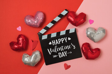 Wall Mural - Happy Valentine's day greeting card with movie clapperboard and shiny heart shapes on red and pink background