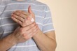 © New Africa - Man applying hand cream on beige background, closeup. Space for text