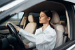 © SHOTPRIME STUDIO - Car, driver, woman, steering wheel, looking at camera a woman is seated in the driver's seat of a vehicle with her hands on the steering wheel, making direct eye contact with the camera