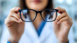 © olenap - Doctors hands holds glasses. Stylish eyewear with reflection in lenses of glasses. symbolizing vision correction and modern style. Optical store or vision correction concept.