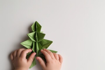 Origami Christmas tree made with child hands on plain background, creativity and holiday decor, minimalistic art, paper folding, DIY craft concept