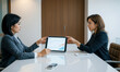 © RooftopStudioBangkok - Two businesswomen discussing data on tablet in modern office setting, showcasing teamwork and collaboration. atmosphere is professional and focused