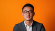 © Dream Decko - Professional portrait of a confident man wearing glasses and a suit against a vibrant orange background
