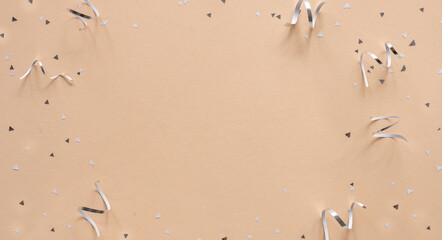 Wall Mural - close up on group of silver color of rolling ribbon and confetti on beige background with copy space