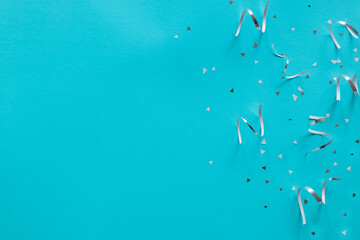 Wall Mural - close up on group of silver color of rolling ribbon and confetti on teal background with copy space 