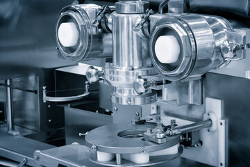 Poster - A machine with two round parts and a white part. The machine is silver