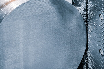 Fototapete - A large piece of metal with a blue surface. The surface is covered with small holes. The metal is being cut by a machine