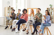 © Studio Romantic - Multiracial group of happy young people sitting on chairs in row, applauding to speaker after work meeting or training. Grateful diverse team of company employees clapping hands to colleague or coach.