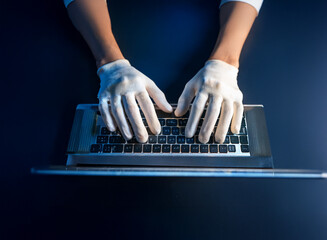 Aufkleber - Overhead view of hands in white gloves typing on a laptop keyboard in low light.  Suggests secrecy, digital security, or clandestine activity.