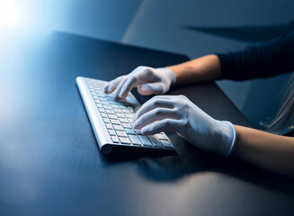 Aufkleber - Close-up of hands wearing white gloves typing on a silver keyboard.  The scene is dimly lit, creating a mysterious atmosphere.