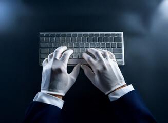 Aufkleber - Overhead view of hands in white gloves typing on a wireless keyboard.  The scene is dimly lit, creating a mysterious atmosphere.